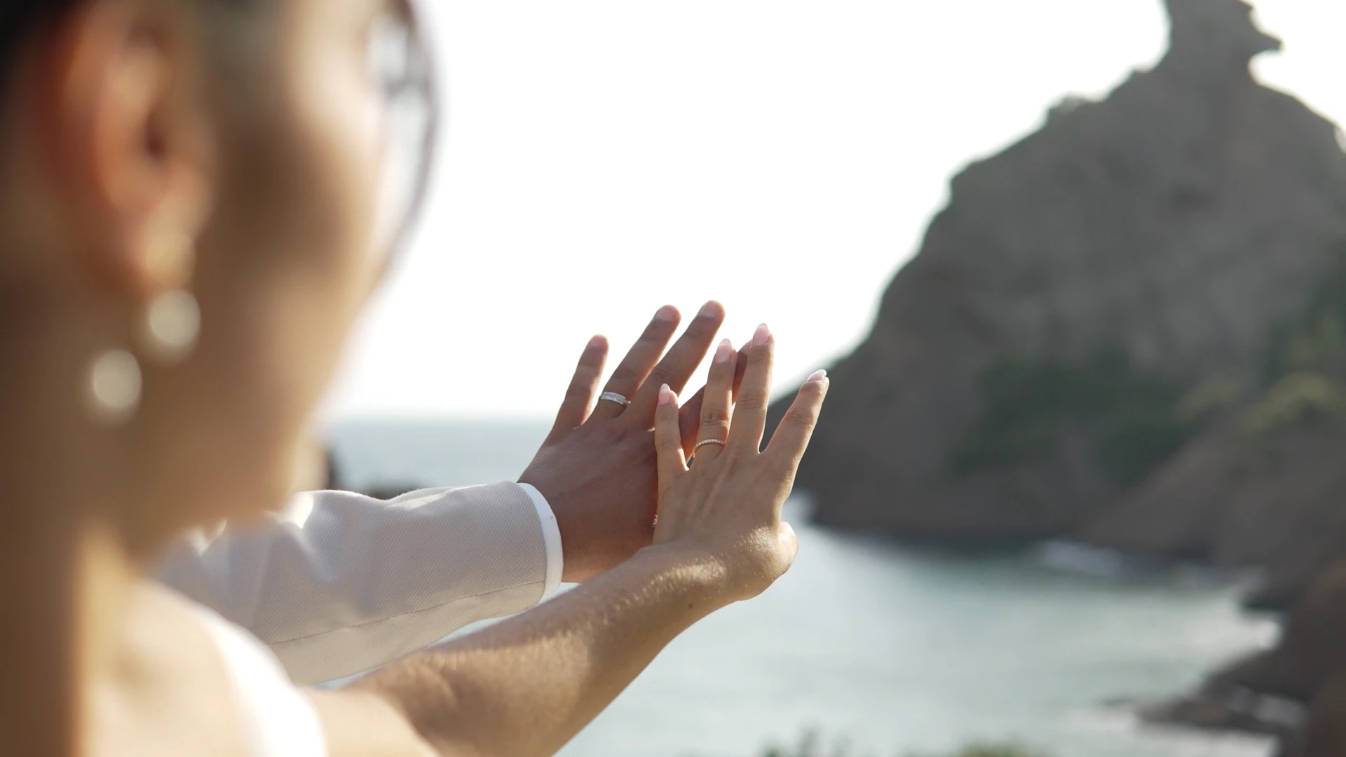 Les mains de la mariée et son alliance, face à la mer