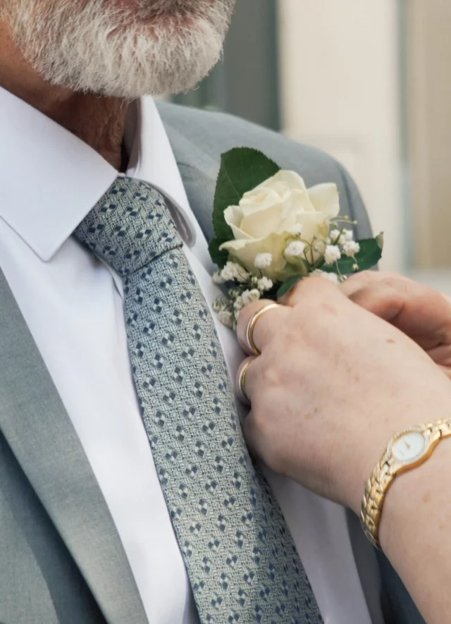 Une main ajuste la boutonnière d’un témoin
