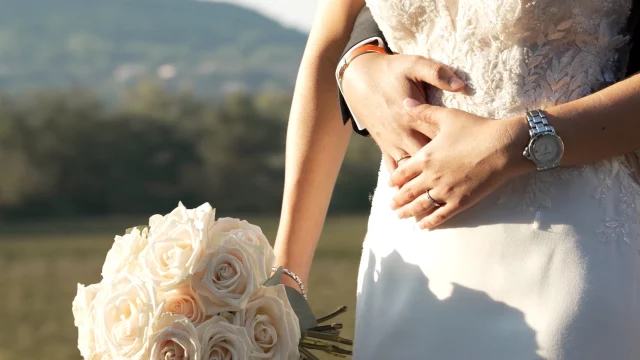 Les mains des mariés et le bouquet de roses blanches