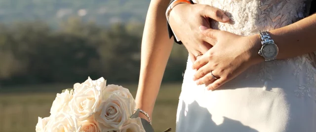 Les mains des mariés et le bouquet de roses blanches